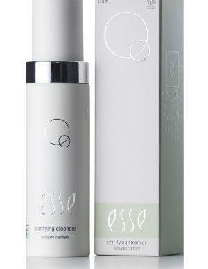 A white bottle of Clarifying Cleanser appears beside its matching box, both with a minimalist design, silver accents, and circular graphics. Labels on the box and bottle are in English and French.