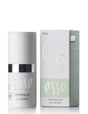 A bottle of Clarifying Oil with a white cap is positioned beside its minimalist box, both showcasing silver accents and circular graphics. The box displays the product name and size: 0.5 fl oz.