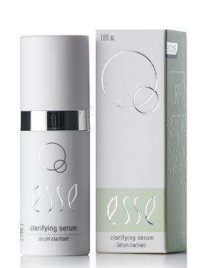 A white bottle of Clarifying Serum stands beside its matching box, both displaying minimalist silver and green accents, circular graphics, and clear English labeling.